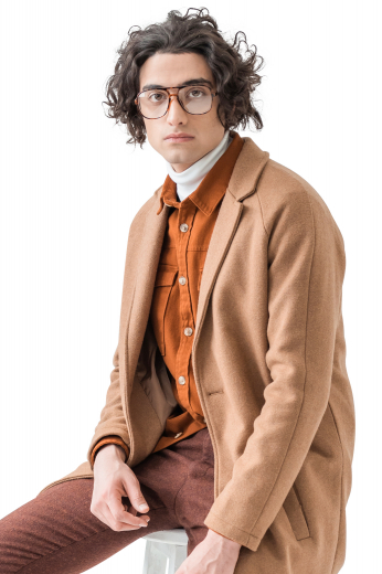 This men's custom made tan colored coat is tailor made in a fine wool and tweed, featuring a single breasted button closure, slanted welt pockets, and a center vent. 