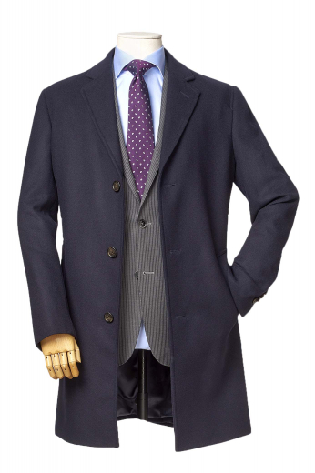 This super elegant mens tailor made dark blue wool overcoat with a single breasted pattern and 3 front close buttons is a stunning formal winter jacket that you can wear to work daily. With a display of trendy hand moulded shoulder and a comfortable finish, this mens bespoke dark blue overcoat also features 2 3-inch-wide edge stitched notch lapels with a boutonniere on the left lapel and 2 slanted edge stitched lower pockets on the front. Buy this mens handmade comfortable overcoat at My custom Tailor at affordable rates.